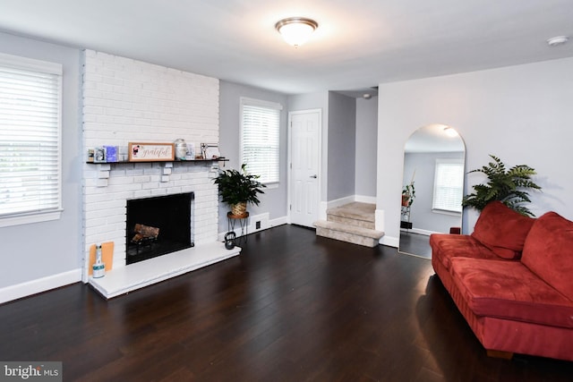 living room featuring a healthy amount of sunlight, a brick fireplace, baseboards, and wood finished floors