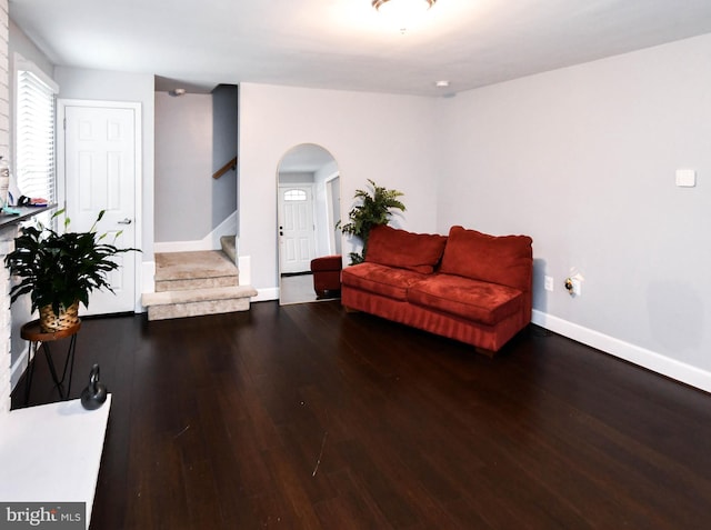 sitting room with baseboards, stairway, arched walkways, and wood finished floors