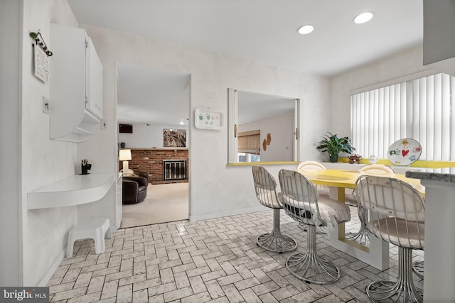 dining room with a fireplace, recessed lighting, brick floor, and baseboards