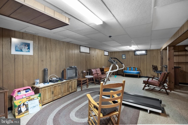 exercise room with wooden walls, a drop ceiling, visible vents, and carpet floors