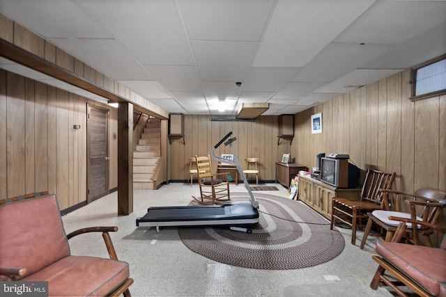 workout room with a paneled ceiling and wood walls