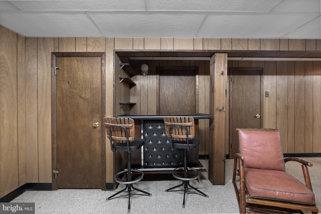 sitting room featuring a dry bar, baseboards, and wood walls