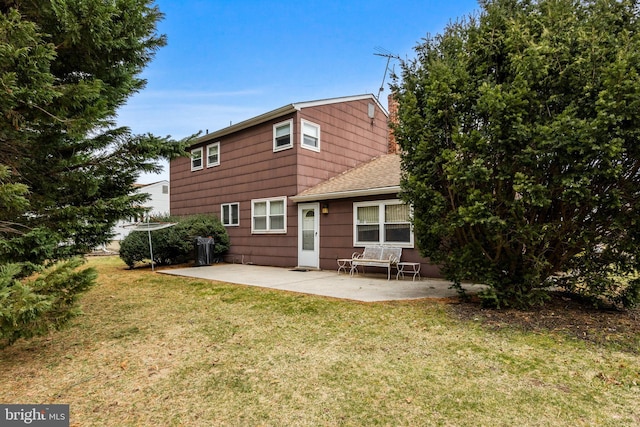 rear view of property with a shingled roof, a patio, a yard, and a chimney