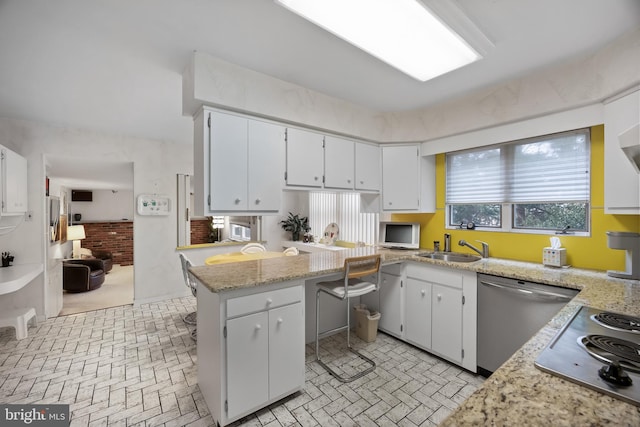 kitchen with white cabinets, appliances with stainless steel finishes, brick patterned floor, and a sink