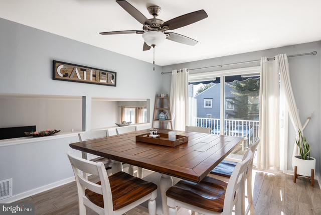 dining space with ceiling fan, wood finished floors, visible vents, and baseboards