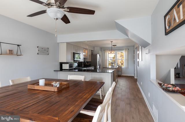 dining area featuring a toaster, visible vents, baseboards, a ceiling fan, and dark wood-style flooring