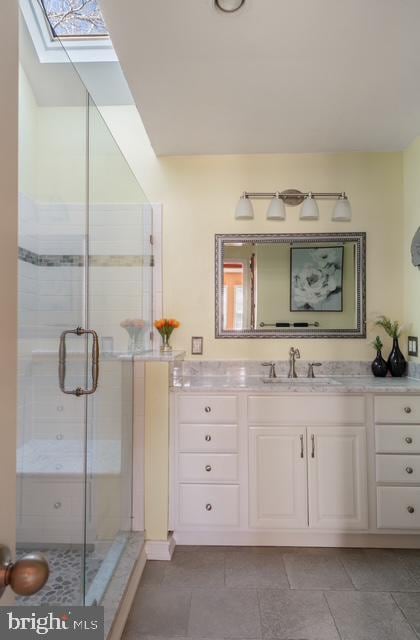 full bath featuring a skylight, vanity, and a shower stall