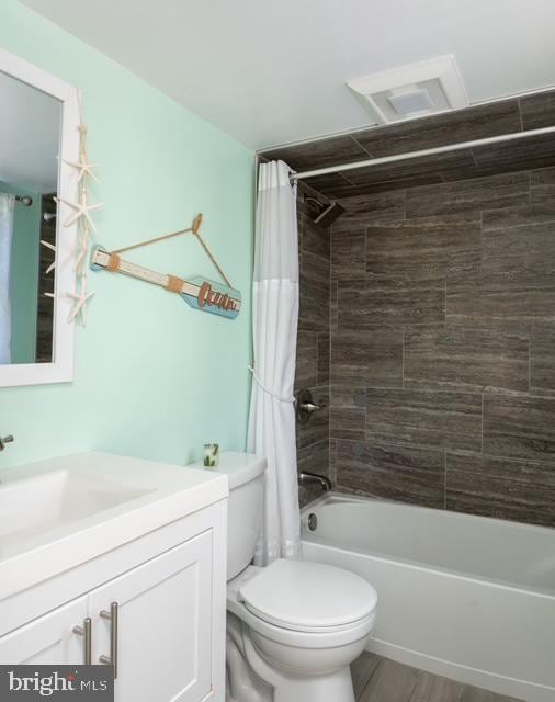 full bath with vanity, wood finished floors, shower / bath combo with shower curtain, and toilet