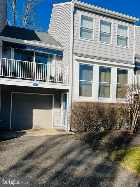 view of front of property with an attached garage, a balcony, and aphalt driveway