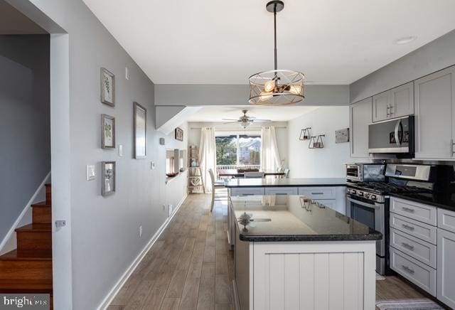 kitchen featuring baseboards, dark wood-style floors, ceiling fan, a peninsula, and stainless steel appliances