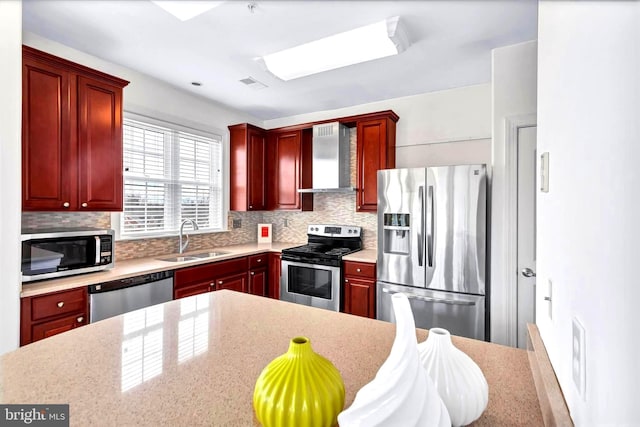 kitchen featuring stainless steel appliances, tasteful backsplash, a sink, wall chimney range hood, and dark brown cabinets