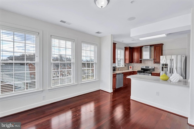 kitchen featuring stainless steel appliances, visible vents, light countertops, and wall chimney range hood