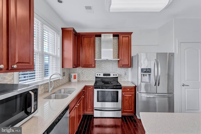 kitchen featuring visible vents, dark wood-style floors, wall chimney exhaust hood, appliances with stainless steel finishes, and a sink