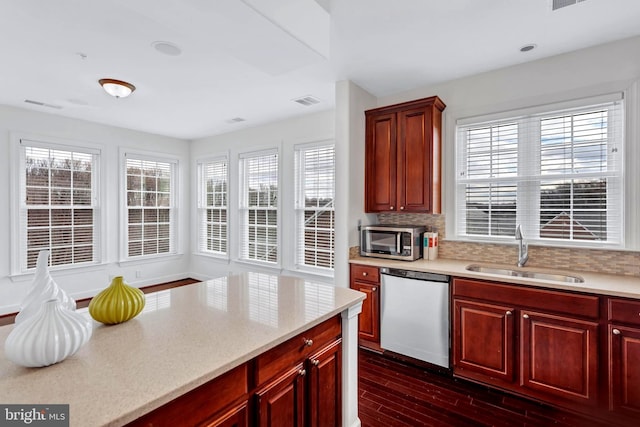 kitchen featuring reddish brown cabinets, visible vents, dishwasher, stainless steel microwave, and a sink