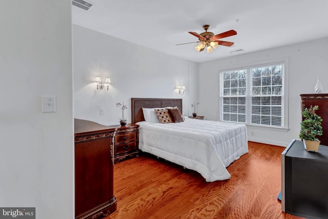 bedroom with a ceiling fan, visible vents, and wood finished floors