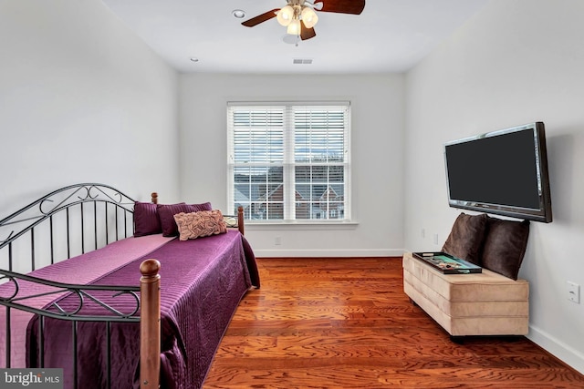 bedroom featuring a ceiling fan, wood finished floors, visible vents, and baseboards