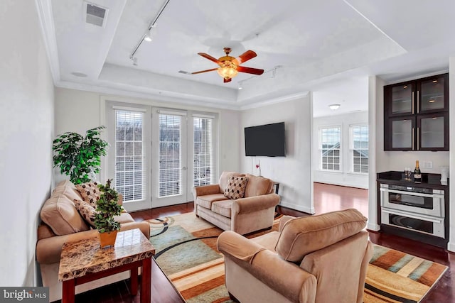 living room featuring visible vents, a tray ceiling, and wood finished floors