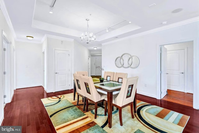 dining room with a chandelier, a raised ceiling, crown molding, and wood finished floors