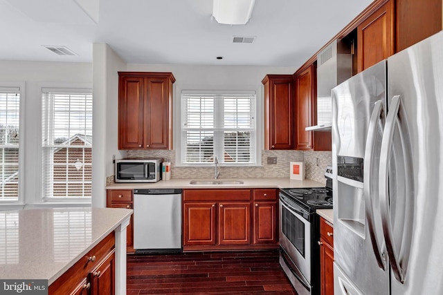 kitchen with dark wood-style flooring, a sink, visible vents, appliances with stainless steel finishes, and decorative backsplash