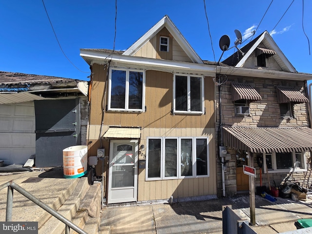 back of house with cooling unit and stone siding