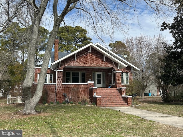 view of front of property featuring a front yard, a chimney, and brick siding