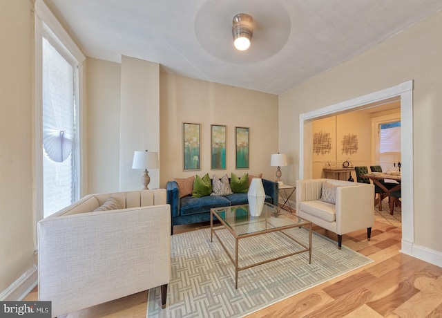 living room featuring a healthy amount of sunlight, ceiling fan, baseboards, and wood finished floors