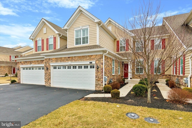 multi unit property featuring a garage, stone siding, and driveway