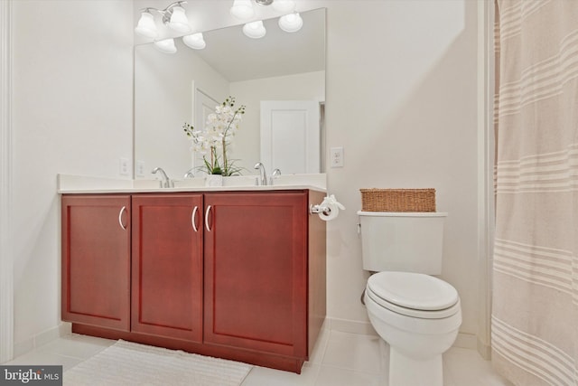 bathroom featuring toilet, a sink, baseboards, tile patterned floors, and double vanity