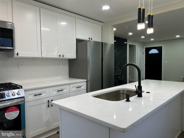 kitchen featuring a sink, a center island with sink, white cabinetry, and stainless steel appliances