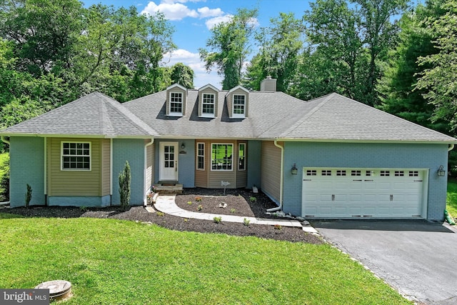 view of front of house featuring a garage, brick siding, a chimney, and a front lawn