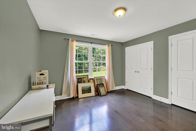 bedroom with a closet, dark wood finished floors, and baseboards