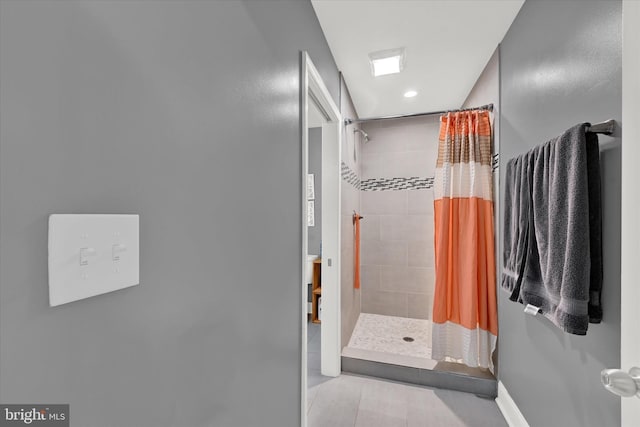 full bathroom with a tile shower and baseboards