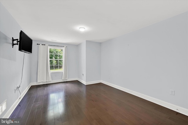 spare room with baseboards and dark wood finished floors