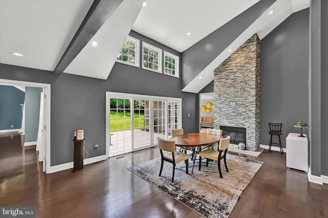 dining space featuring high vaulted ceiling, a stone fireplace, hardwood / wood-style flooring, recessed lighting, and baseboards