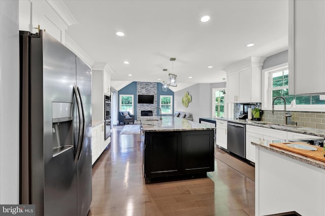 kitchen featuring a kitchen island, appliances with stainless steel finishes, open floor plan, a sink, and backsplash