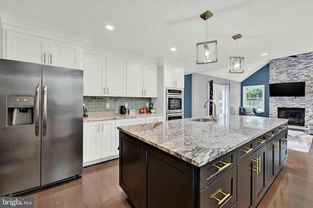 kitchen with appliances with stainless steel finishes, white cabinetry, a sink, and tasteful backsplash