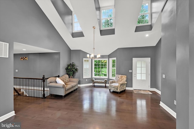 living area with a chandelier, a towering ceiling, baseboards, and wood finished floors