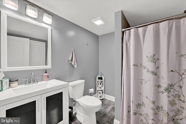 full bath featuring baseboards, a shower with shower curtain, toilet, wood finished floors, and vanity