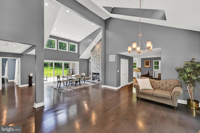 living room featuring dark wood-type flooring, visible vents, a notable chandelier, and a stone fireplace