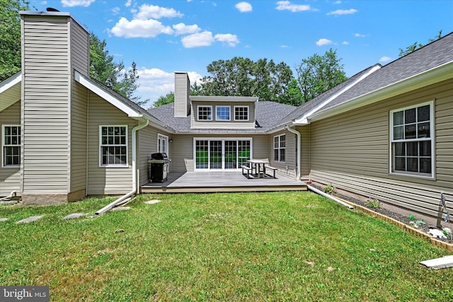 rear view of house featuring a deck, a yard, a shingled roof, and a chimney