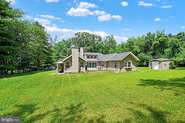 rear view of house featuring a yard, a storage unit, a chimney, and an outdoor structure