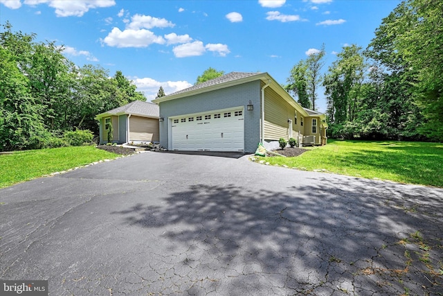 view of front of home featuring a garage, brick siding, driveway, and a front lawn