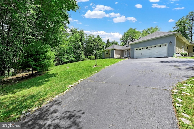 single story home featuring an attached garage, aphalt driveway, and a front yard