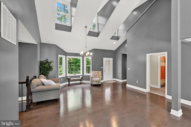 living room featuring a chandelier, high vaulted ceiling, a skylight, wood finished floors, and baseboards