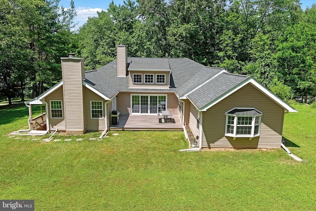 back of property with a deck, a yard, a chimney, and a shingled roof