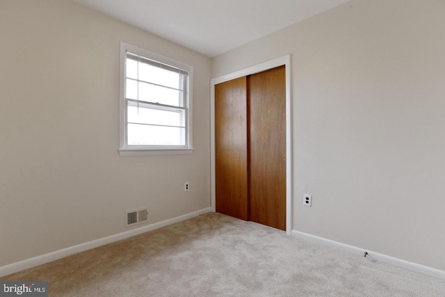 unfurnished bedroom with carpet floors, a closet, visible vents, and baseboards