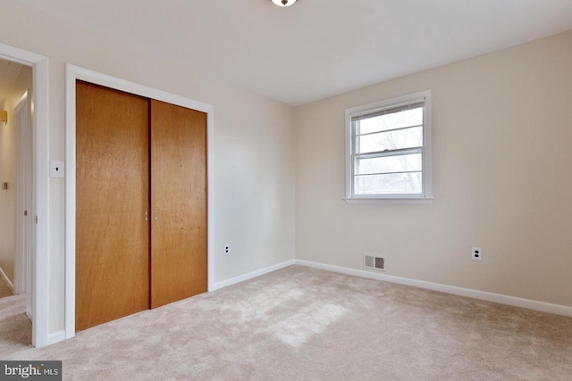 unfurnished bedroom with carpet, a closet, visible vents, and baseboards