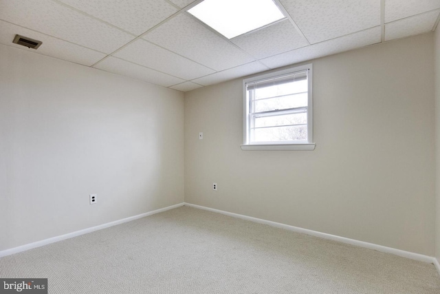 empty room with baseboards, visible vents, a drop ceiling, and carpet flooring