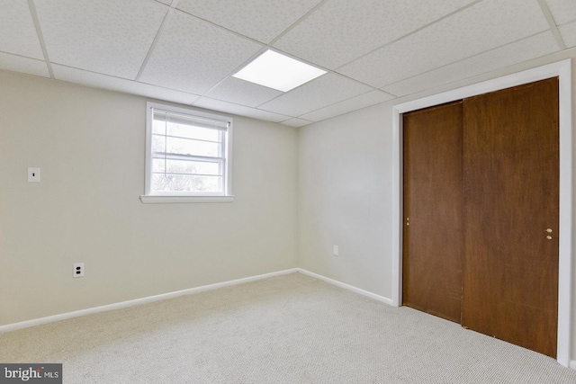 unfurnished bedroom with carpet floors, a closet, a drop ceiling, and baseboards