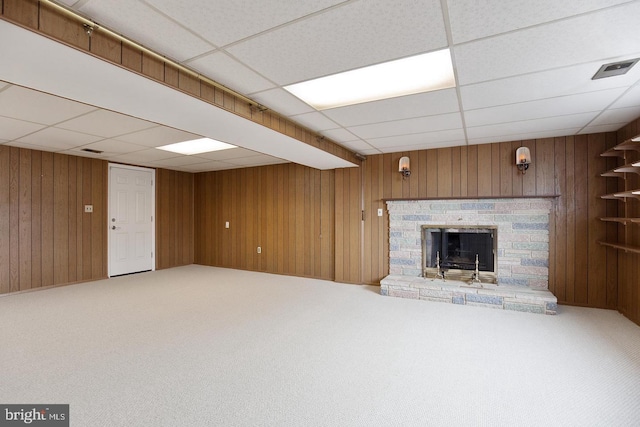 unfurnished living room with a fireplace with raised hearth, carpet floors, and wooden walls